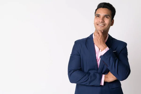 Portrait of young happy Indian businessman in suit thinking — Stock Photo, Image