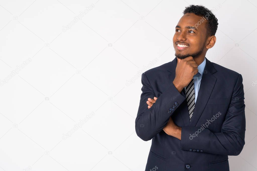 Portrait of happy young African businessman in suit thinking