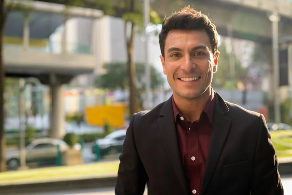 Rostro de feliz joven guapo empresario hispano sonriendo en la ciudad — Foto de Stock