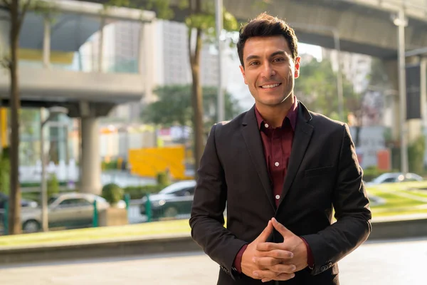 Jonge gelukkig Hispanic zakenman glimlachend in de straten van de stad — Stockfoto