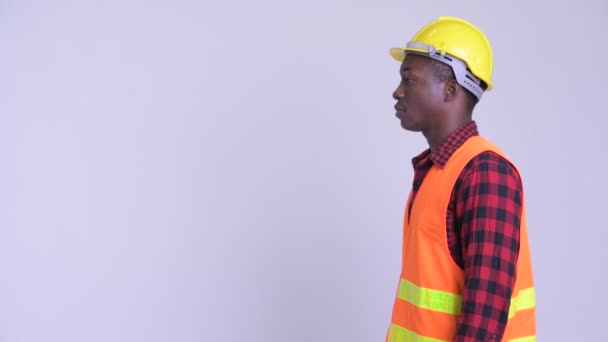 Vista del perfil del joven y feliz trabajador de la construcción africano pensando — Vídeos de Stock