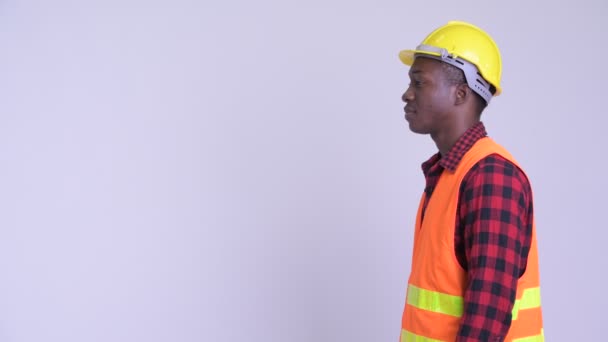 Перегляд профілю щасливий молодий Африканський чоловік будівельний працівник з зброєю схрещені — стокове відео