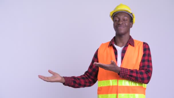 Joven feliz africano trabajador de la construcción mostrando algo — Vídeo de stock