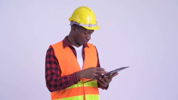 Joven feliz africano trabajador de la construcción sosteniendo portapapeles y dando pulgares hacia arriba — Vídeo de stock