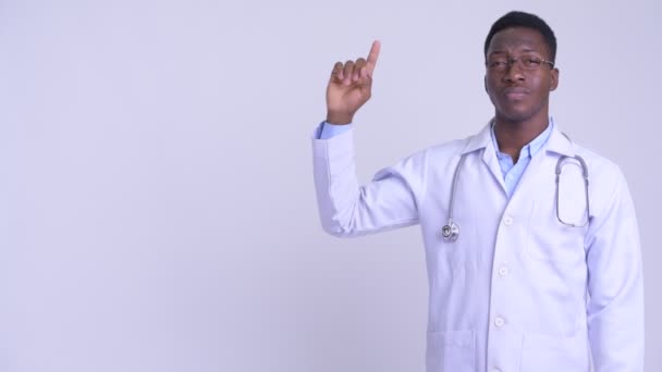 Joven hombre africano feliz médico pensando y señalando hacia arriba — Vídeos de Stock