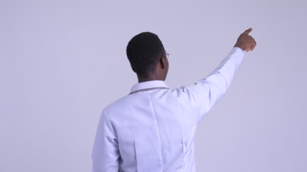 Rückansicht junger glücklicher afrikanischer Arzt führt Regie, während er Klemmbrett hält — Stockvideo