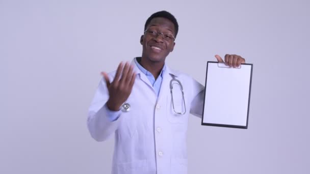 Joven hombre africano feliz médico mostrando portapapeles y dando pulgares hacia arriba — Vídeos de Stock