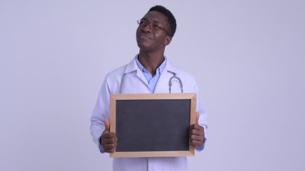 Junger glücklicher afrikanischer Mann denkt beim Halten einer Tafel — Stockvideo