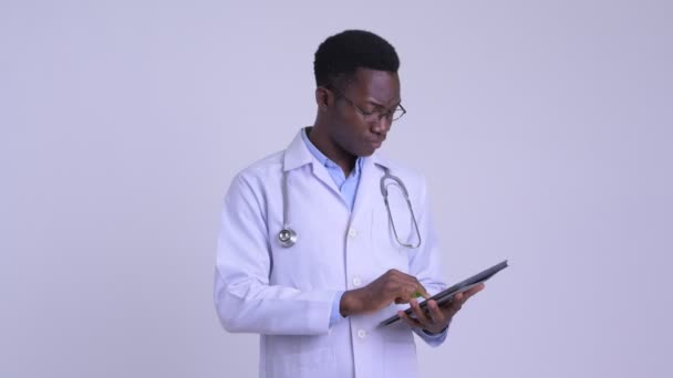 Giovane felice uomo africano medico pensando durante l'utilizzo di tablet digitale — Video Stock