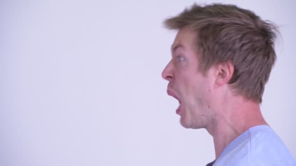 Лицо напряженного молодого человека, который выглядит сердитым и кричащим — стоковое видео