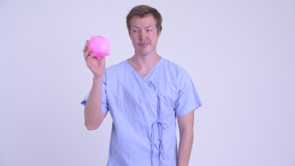 Benadrukt jongeman patiënt piggy bank holding en duimen neer geven — Stockvideo