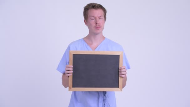 Lycklig ung man tålamod tänkande medan du håller Blackboard — Stockvideo