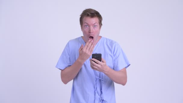 Portrait of young man patient using phone and looking shocked — Stock Video