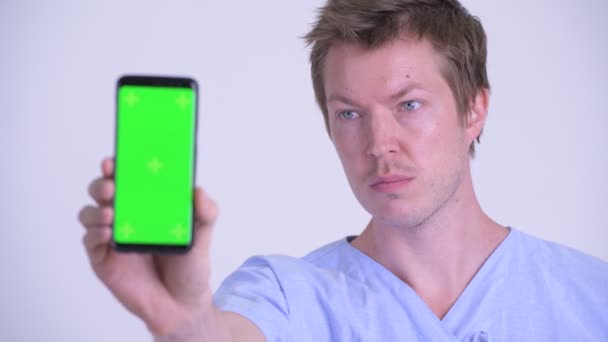 Gezicht van gelukkige jonge man patiënt toont telefoon — Stockvideo