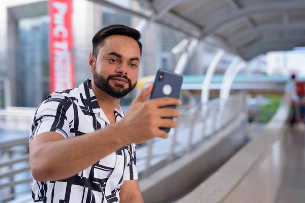 Jeune homme indien barbu prenant selfie sur la passerelle à l'extérieur — Photo