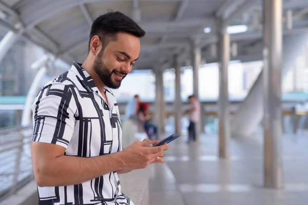 Ευτυχισμένος νέος Ινδικό μούσι άνθρωπος χρησιμοποιώντας το τηλέφωνο στην γέφυρα του εξωτερικού — Φωτογραφία Αρχείου