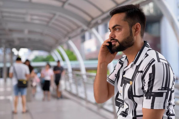Heureux jeune homme indien barbu parlant au téléphone à la passerelle — Photo