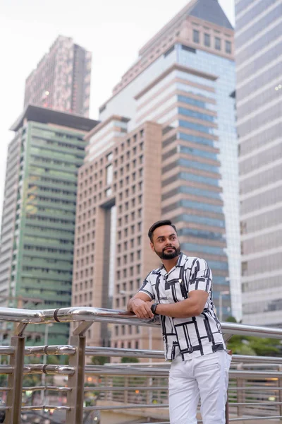 Joven barbudo indio pensando en contra de la vista de la ciudad — Foto de Stock