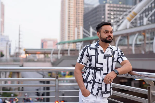 Joven barbudo indio pensando en contra de la vista de la ciudad al aire libre — Foto de Stock