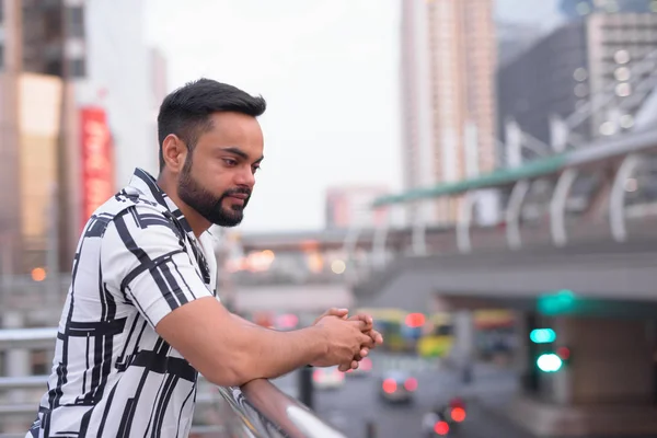 Profilbild eines jungen bärtigen indischen Mannes, der auf die Stadt im Freien herabblickt — Stockfoto