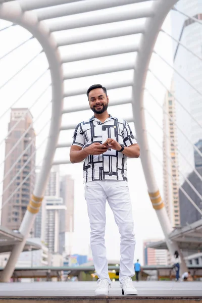 Bote de cuerpo entero de feliz joven barbudo indio sonriendo en la ciudad — Foto de Stock