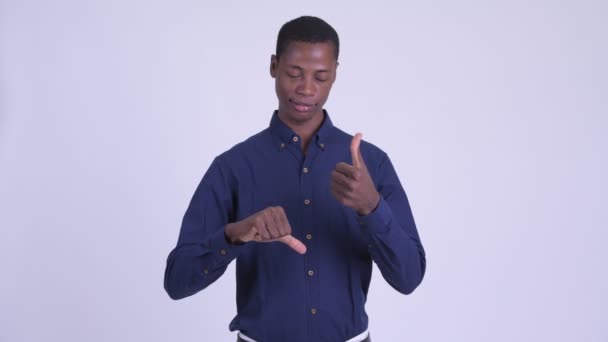 Молодой запутавшийся африканский бизнесмен выбирает между большим и большим пальцами вниз — стоковое видео
