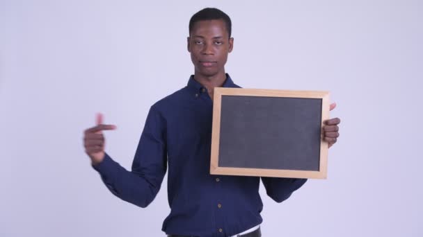 Young benadrukt Afrikaanse zakenman holding blackboard en duimen neer geven — Stockvideo