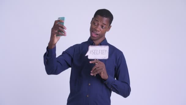 Young happy African businessman taking selfie with paper sign — Stock Video