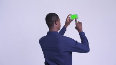 Telefon ile resim çekerken genç mutlu Afrikalı işadamı arka görünümü