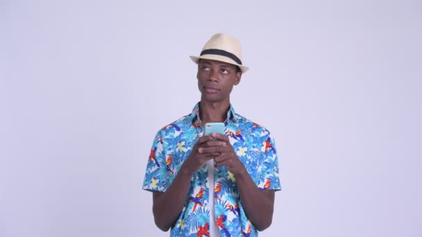 Joven hombre turístico africano feliz pensando mientras usa el teléfono — Vídeos de Stock
