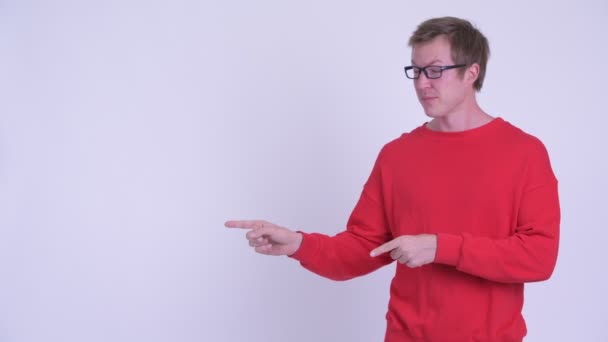 Šťastný mladý pohledný muž ukazující prstem a něco — Stock video