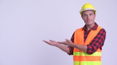 Genç mutlu Ispanyol adam inşaat işçisi bir şey gösteren