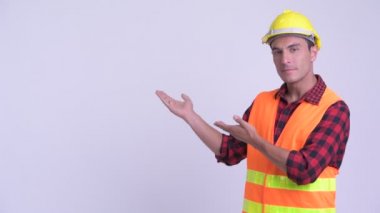Genç mutlu Ispanyol adam inşaat işçisi arka bir şey gösteren