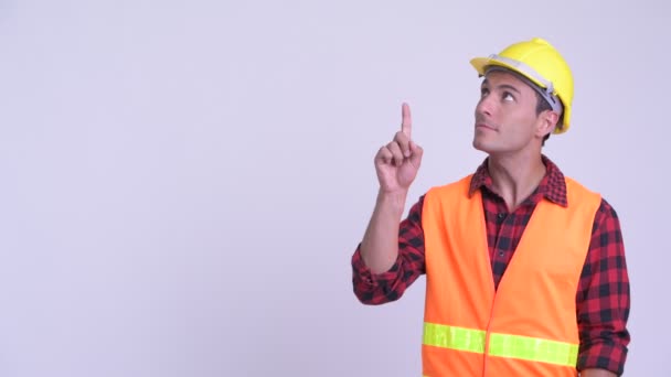 Jonge gelukkige Hispanic man Construction Worker denken terwijl omhoog te wijzen — Stockvideo