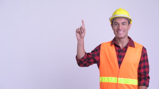 Joven feliz hispano trabajador de la construcción apuntando hacia arriba — Vídeos de Stock