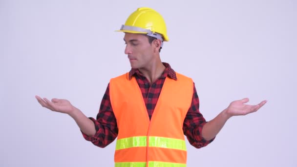 Young happy Hispanic man construction worker comparing something — Stock Video