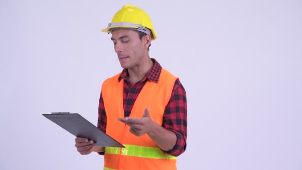 Joven feliz trabajador de la construcción hispano hablando mientras lee en el portapapeles — Vídeos de Stock