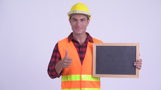 Genç mutlu Ispanyol adam inşaat işçisi tutan tahta ve vermek thumbs yukarı — Stok video