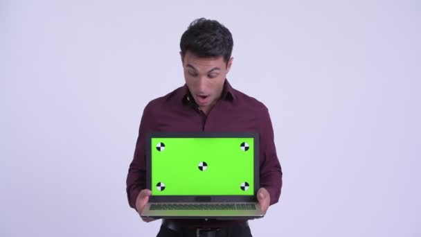 Молодой счастливый латиноамериканец показывает ноутбук и выглядит удивлённым — стоковое видео