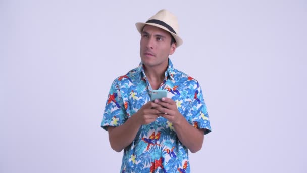 Young happy Hispanic tourist man thinking while using phone — Stock Video