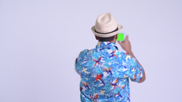 Vista trasera de un joven turista hispano feliz tomando una foto con el teléfono — Vídeos de Stock