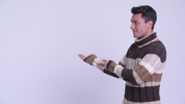 Giovane uomo ispanico felice mostrando qualcosa sul retro pronto per l'inverno — Video Stock