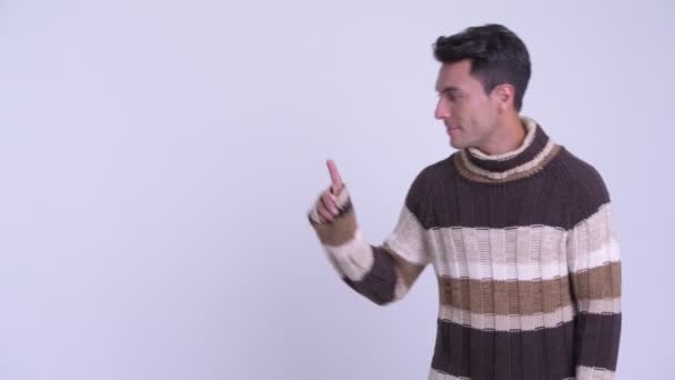 Young happy Hispanic man touching something and giving thumbs up ready for winter — Stock Video