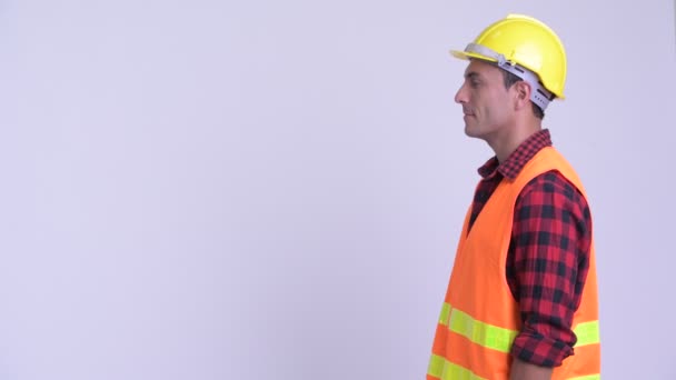 Vista del perfil del joven feliz trabajador de la construcción hispano feliz sonriendo — Vídeos de Stock