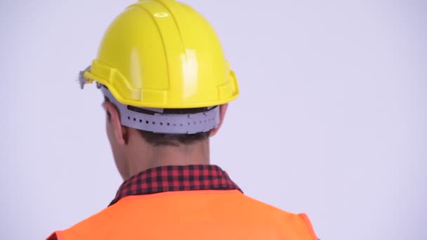 戻って振り返る若い幸せなヒスパニック系の男性建設労働者の背面図 — ストック動画