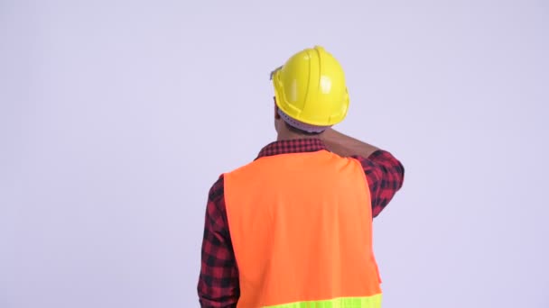 Вид сзади на молодого латиноамериканца строителя, направляющего и указывающего пальцем — стоковое видео