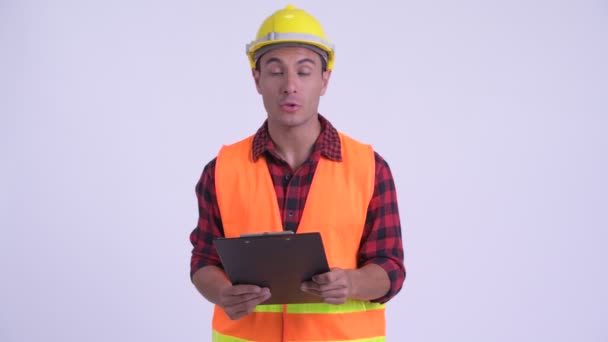 Młody szczęśliwy Hiszpan robotnik budowlany rozmawia podczas czytania w schowku — Wideo stockowe