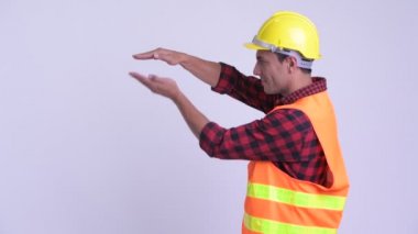 Genç mutlu Ispanyol adam inşaat işçisi parmaklar yakalamaya ve bir şey gösteren