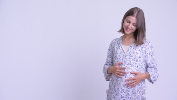 Happy young pregnant woman showing something to the back — Stock Video