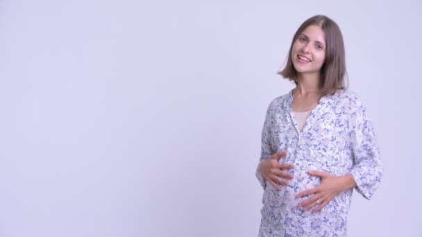 Happy young pregnant woman snapping fingers and showing something — Stock Video